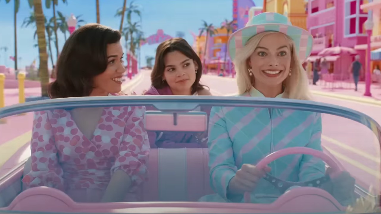 Von links nach rechts: America Ferrera auf der Schrotflinte, Ariana Greenblatt auf dem Rücksitz und Margot Robbie am Steuer des Barbie-Autos im Barbie Land.