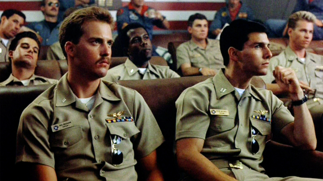 Les personnages de Top Gun d'Anthony Edwards et Tom Cruise participent à un débriefing avec d'autres officiers