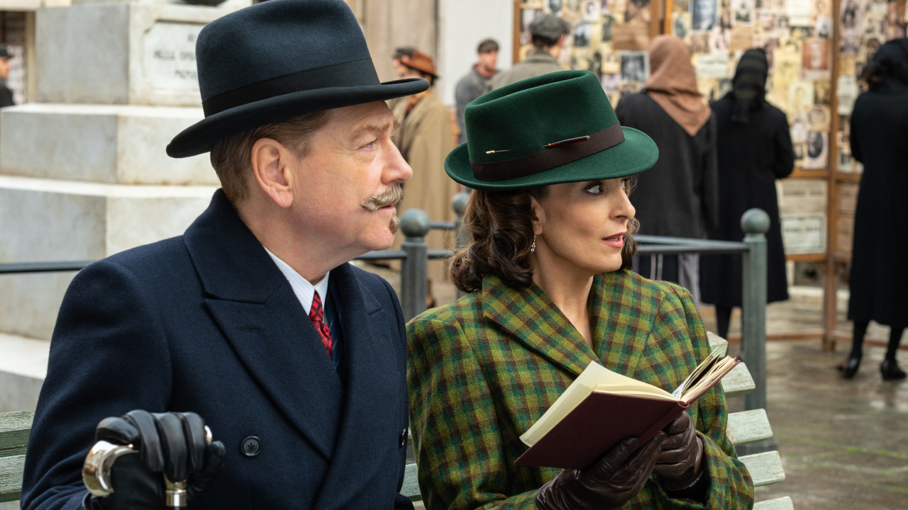 Kenneth Branagh und Tina Fey sitzen auf dem Platz und rezensieren ein Buch in „Ein Spuk in Venedig“.