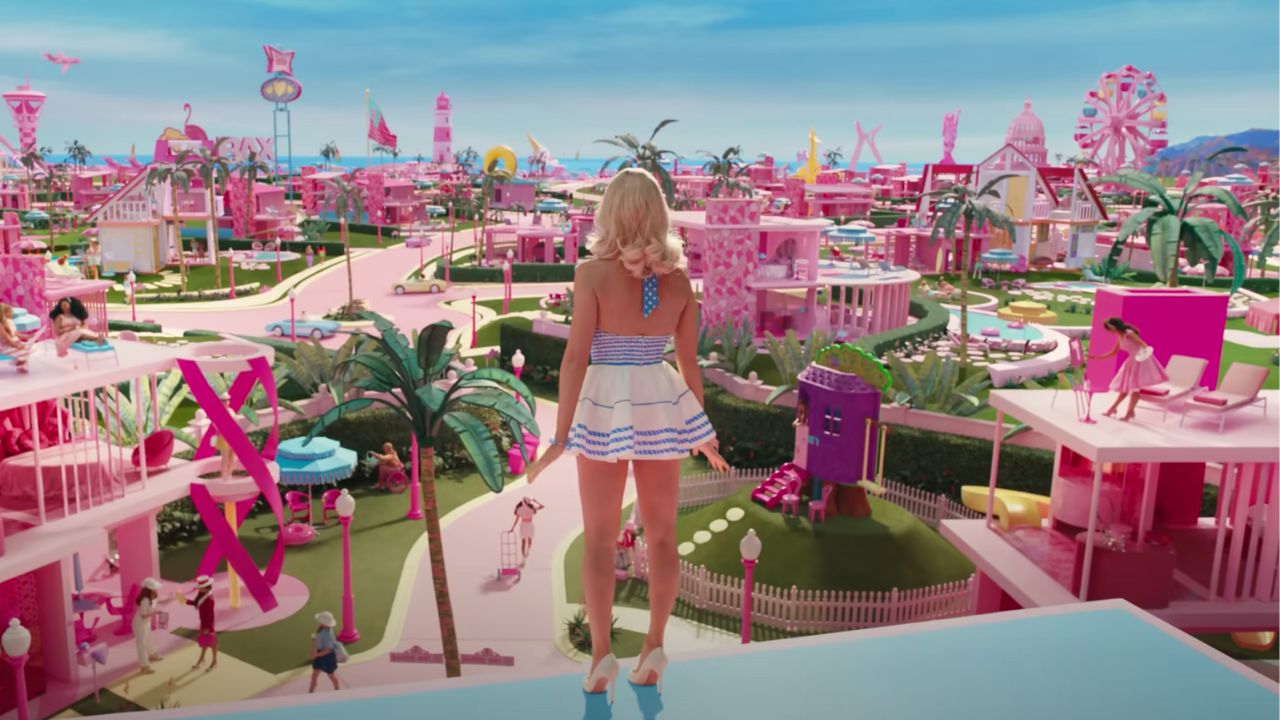 Rückaufnahme von Barbie mit Blick auf die Barbie-Welt von ihrem Traumhaus aus