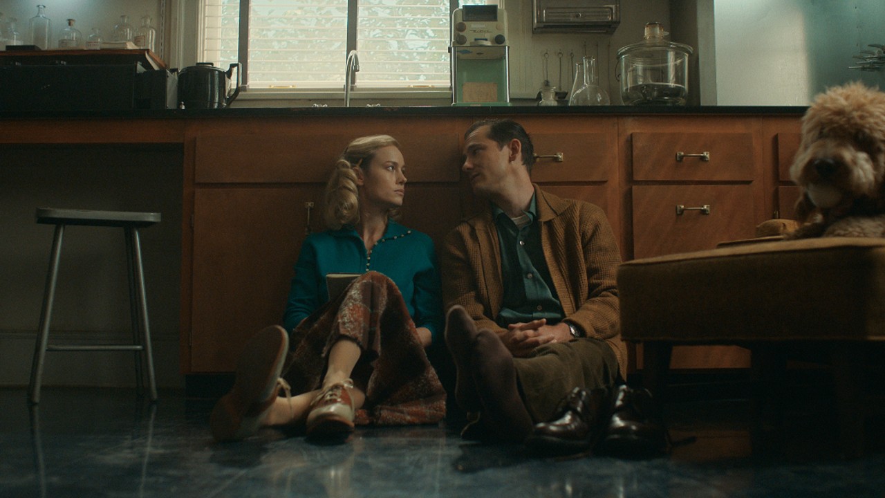 Une photo de presse de Lessons in Chemistry de Brie Larson et Lewis Pullman assis par terre.