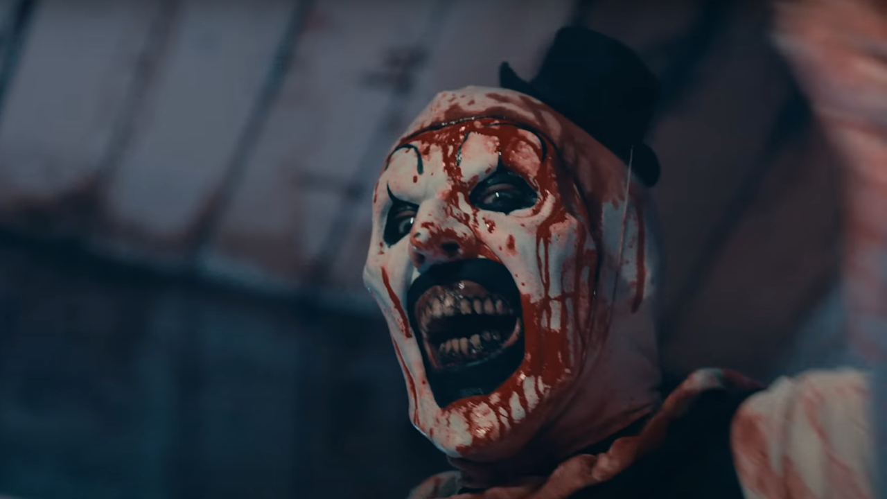 David Howard Thornton lächelt, während er in Terrifier 2 mit Blut bespritzt ist.