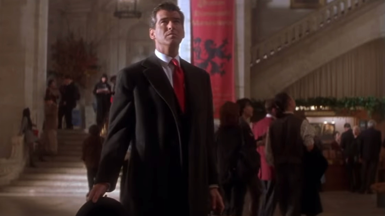 Pierce Brosnan steht in „The Thomas Crown Affair“ gut gekleidet in der Museumslobby.