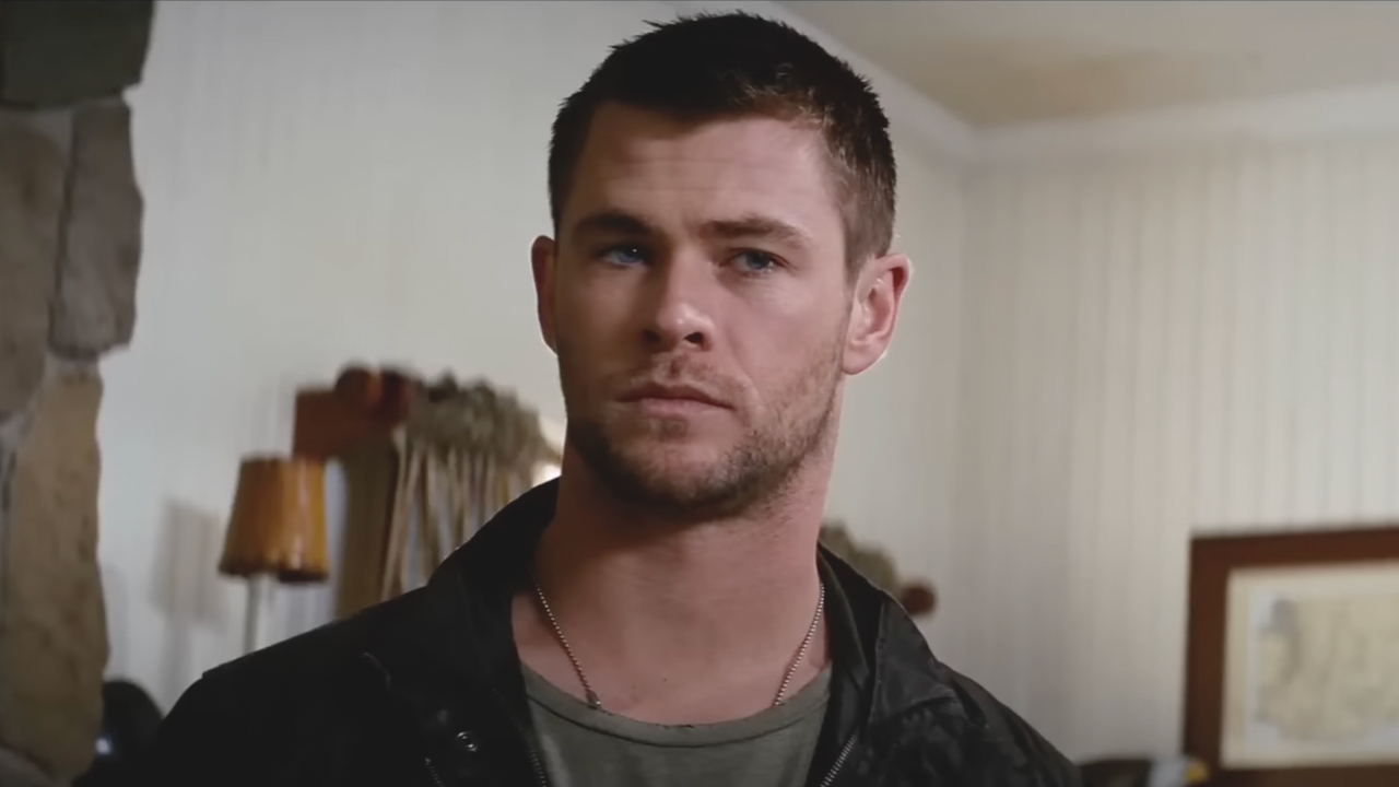 Chris Hemsworth debout dans un salon avec un air déterminé sur le visage dans Red Dawn.