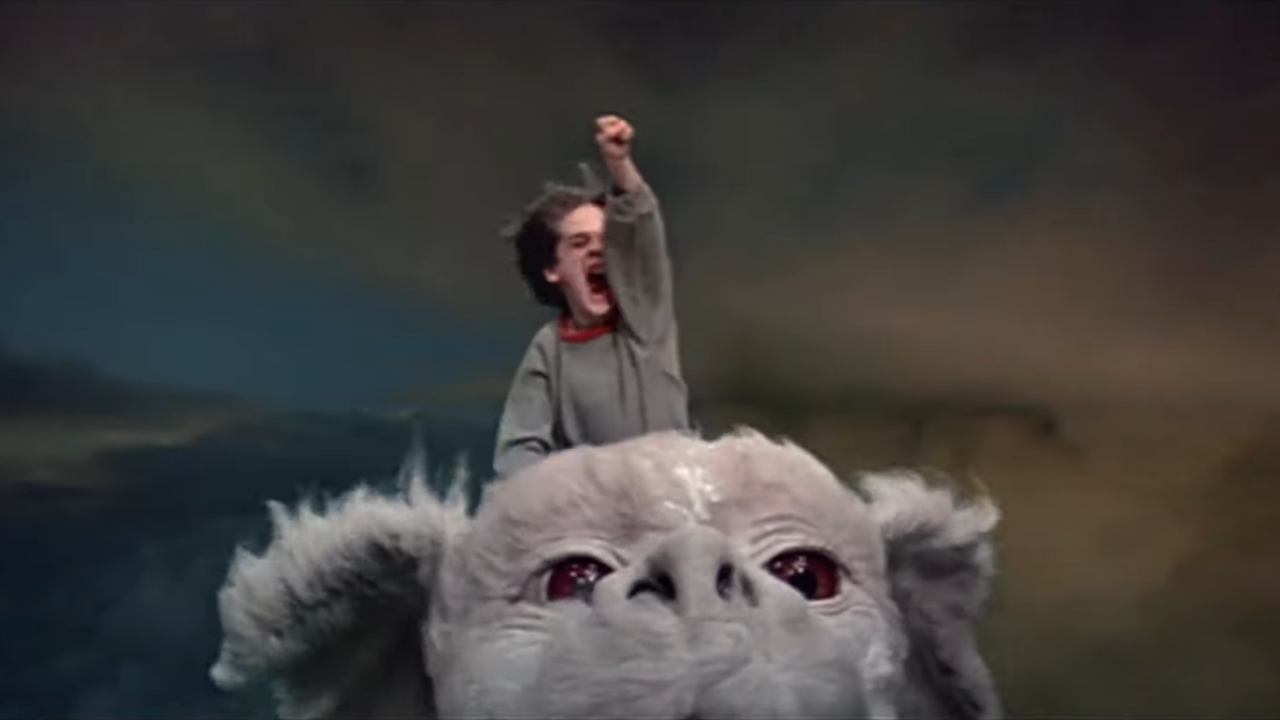 Barret Oliver fliegt in „The NeverEnding Story“ mit erhobener Faust hoch auf Falcor zu.