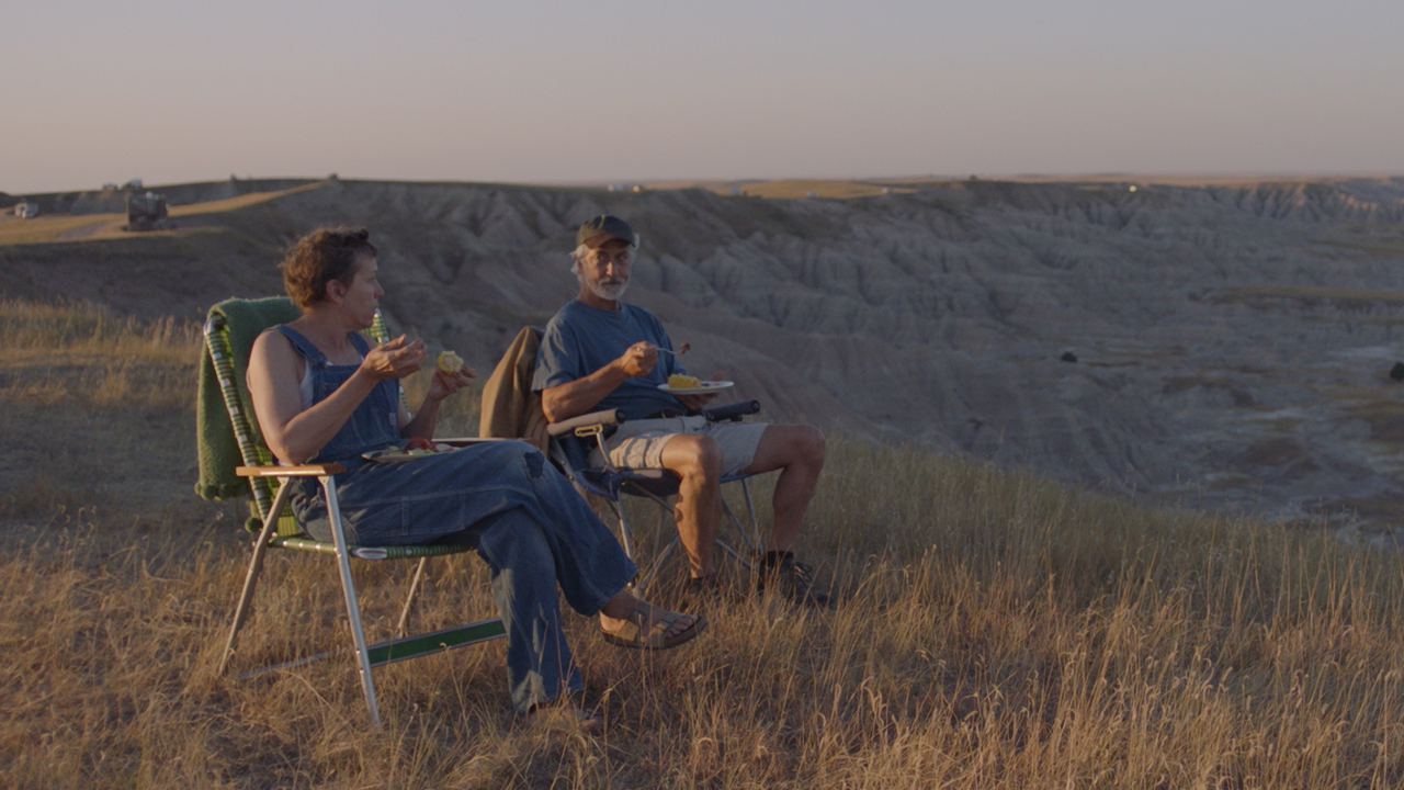 Frances McDormand et David Strathairn mangeant ensemble en plein air à Nomadland.